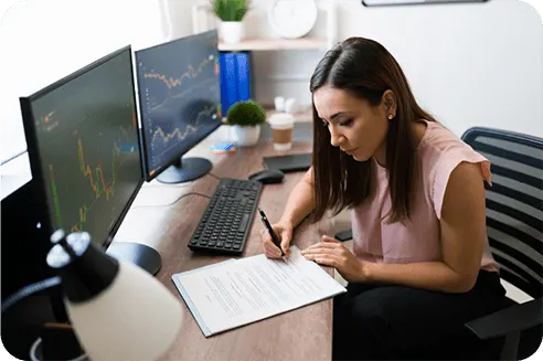 woman at desk with computer taking notes
